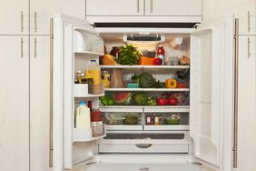 Refrigerator with open doors showing shelves stocked with various fresh produce and packaged food items