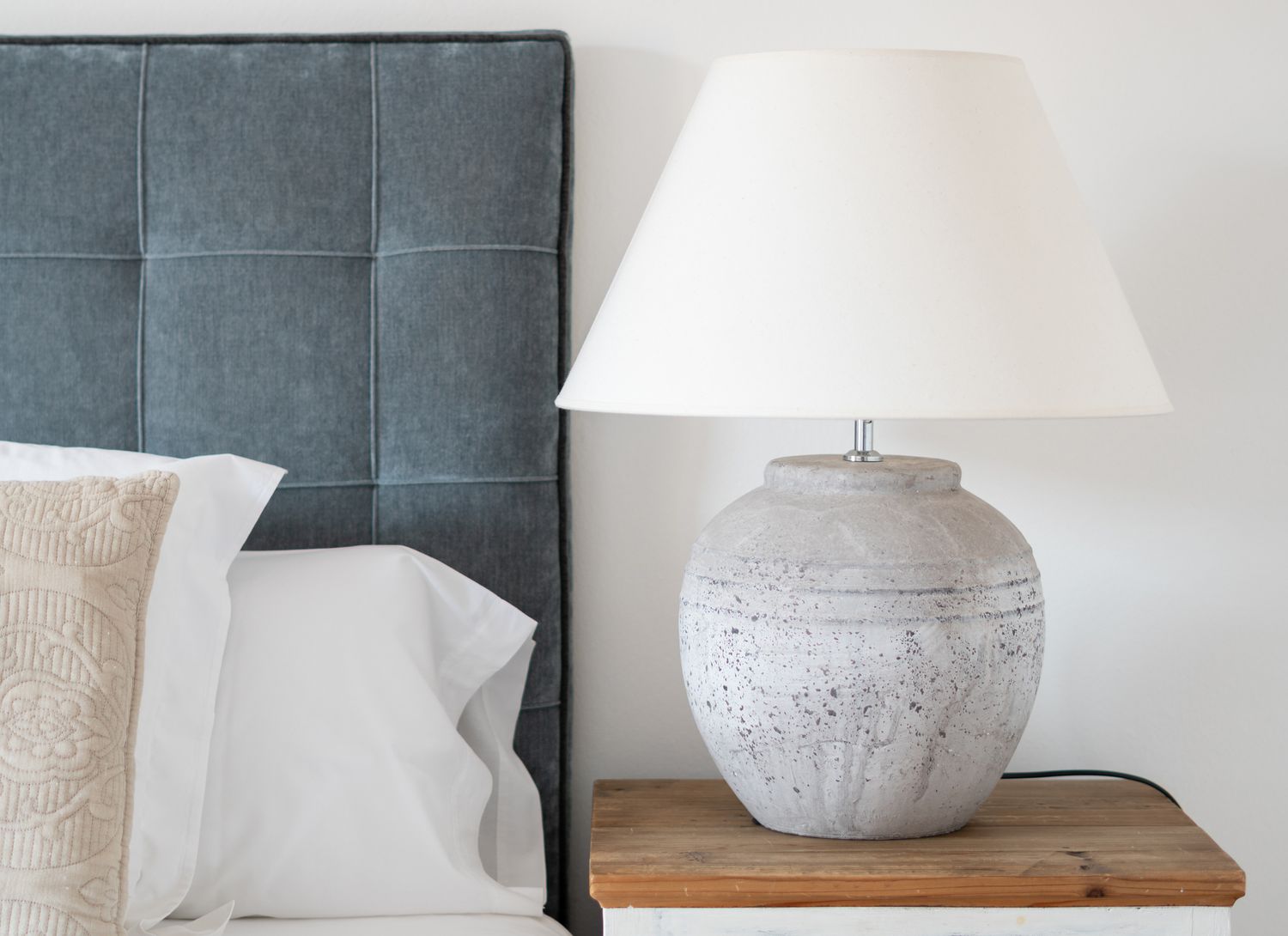 modern lamp on a nightstand next to blue headboard
