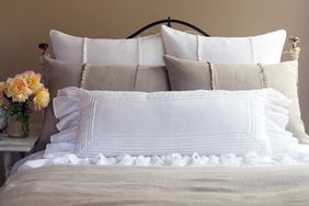 Bed with multiple pillows and a bouquet of flowers on a side table