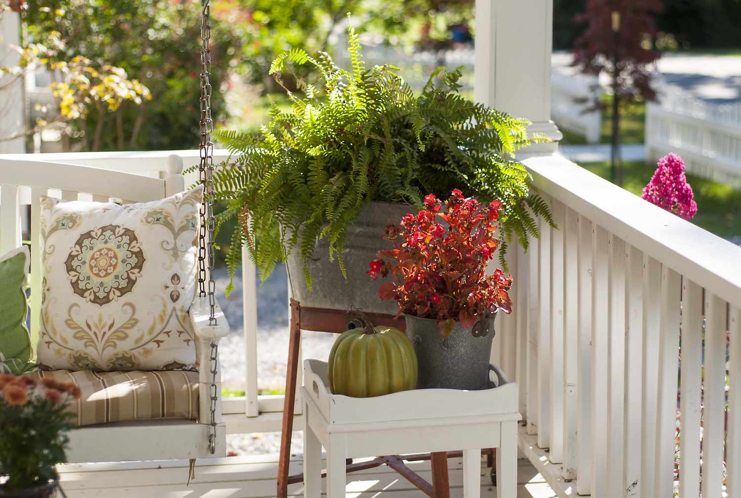 Front porch with a chair potted plants and a decorative pumpkin