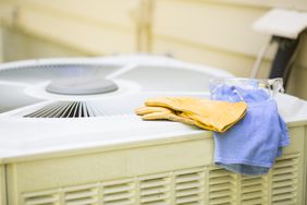 Gloves and cleaning cloth on top of an HVAC unit