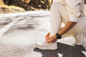 Woman tying white tennis shoes