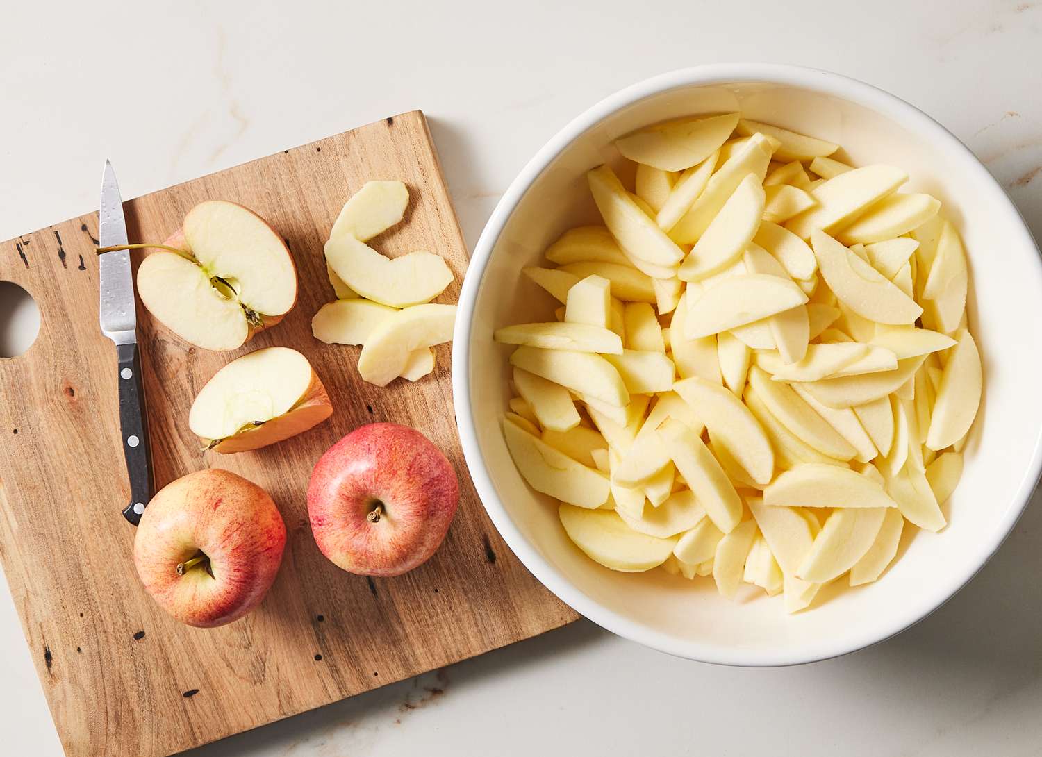 overhead view of cutting board, apples and sliced apples in dish
