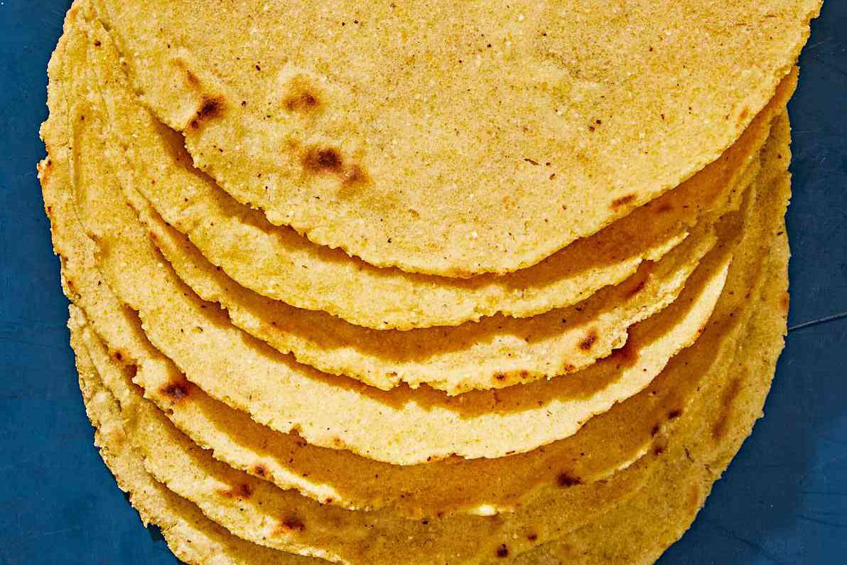 homemade corn tortillas stacked against blue background