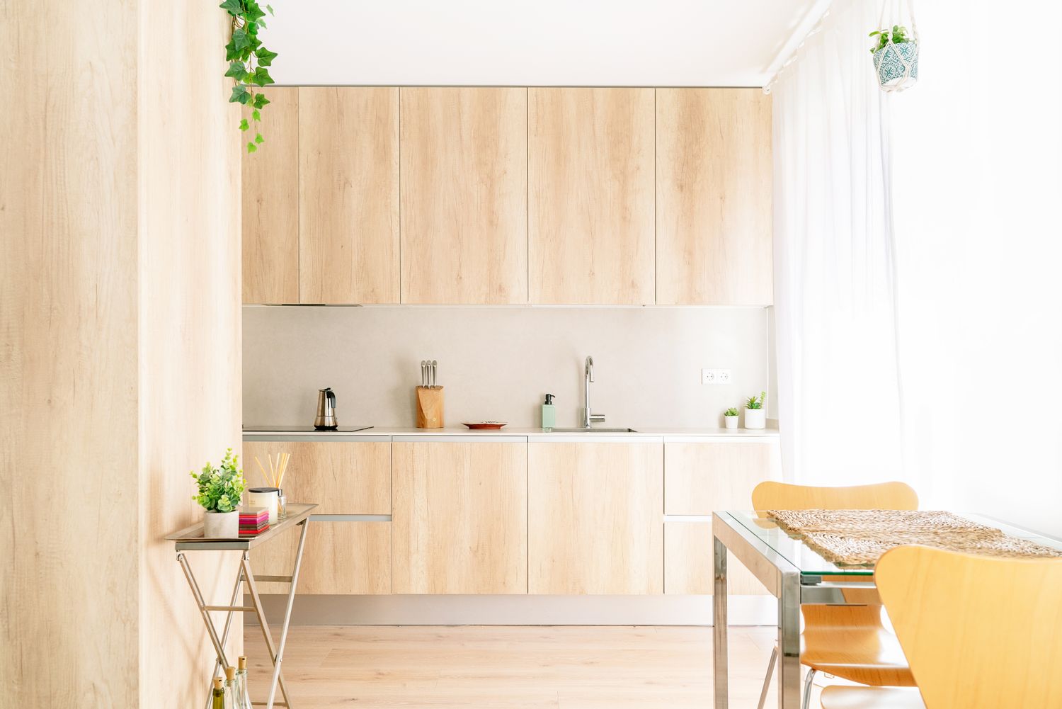 Minimalist kitchen with wooden cabinets a table with chairs and a small trolley