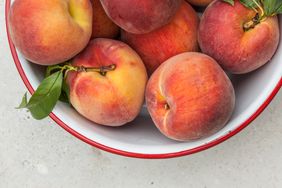 fresh peaches in white metal bowl with red rim