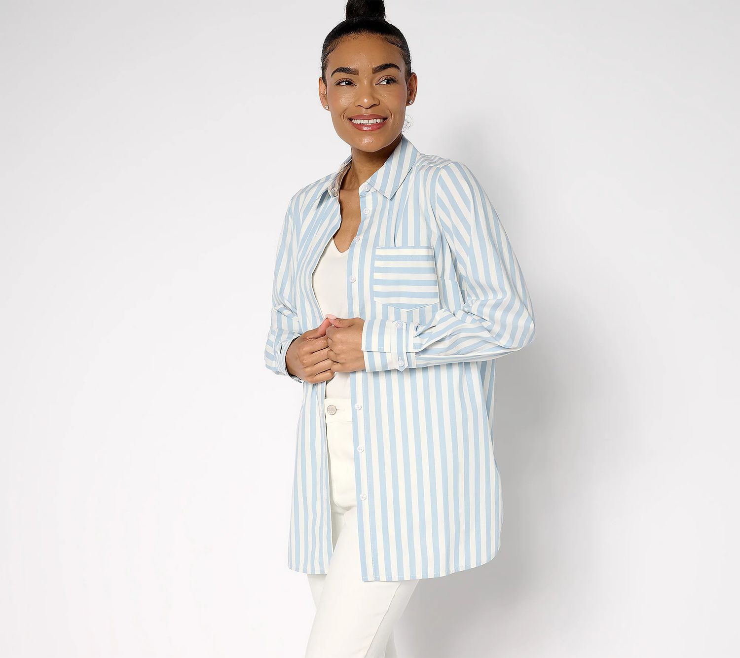 A person wearing a striped shirt over a light undershirt and standing in front of a plain background. 