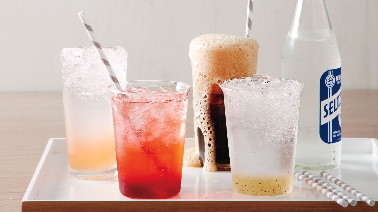 4 glasses of different homemade sodas and a bottle of seltzer