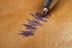 A pen leaving a stain on a leather surface