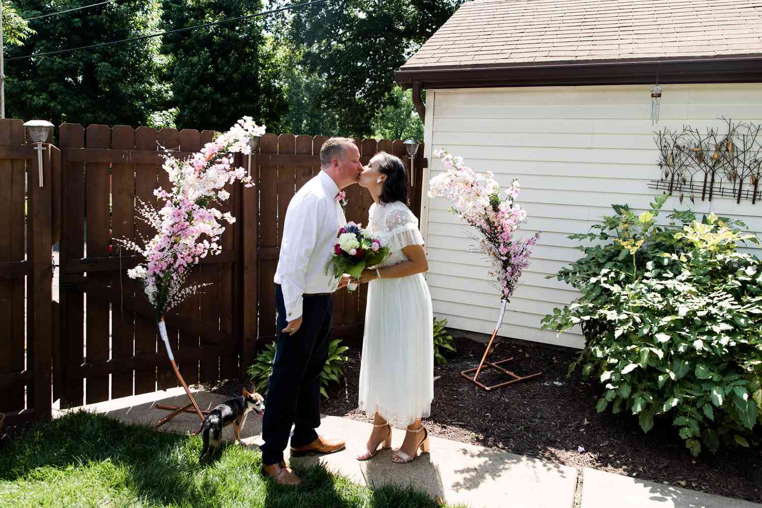 bride and groom sharing ceremonial kiss during backyard wedding