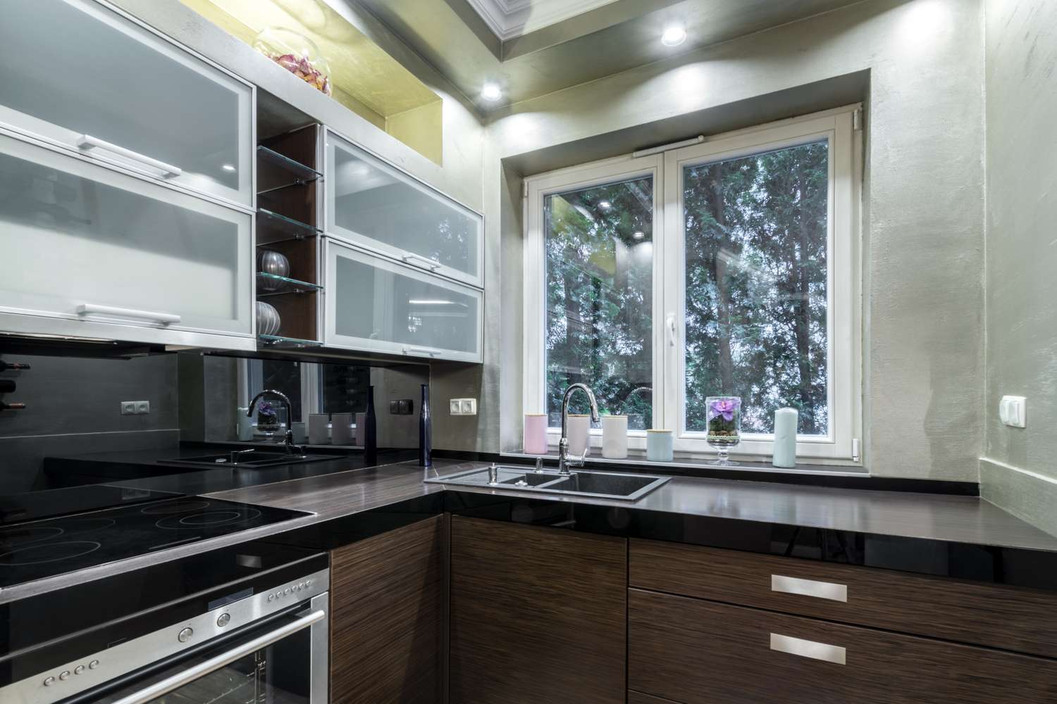 A modern kitchen interior with a sink under a window and dark wooden cabinets