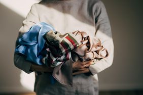 A person holds a bundle of colorful scarves