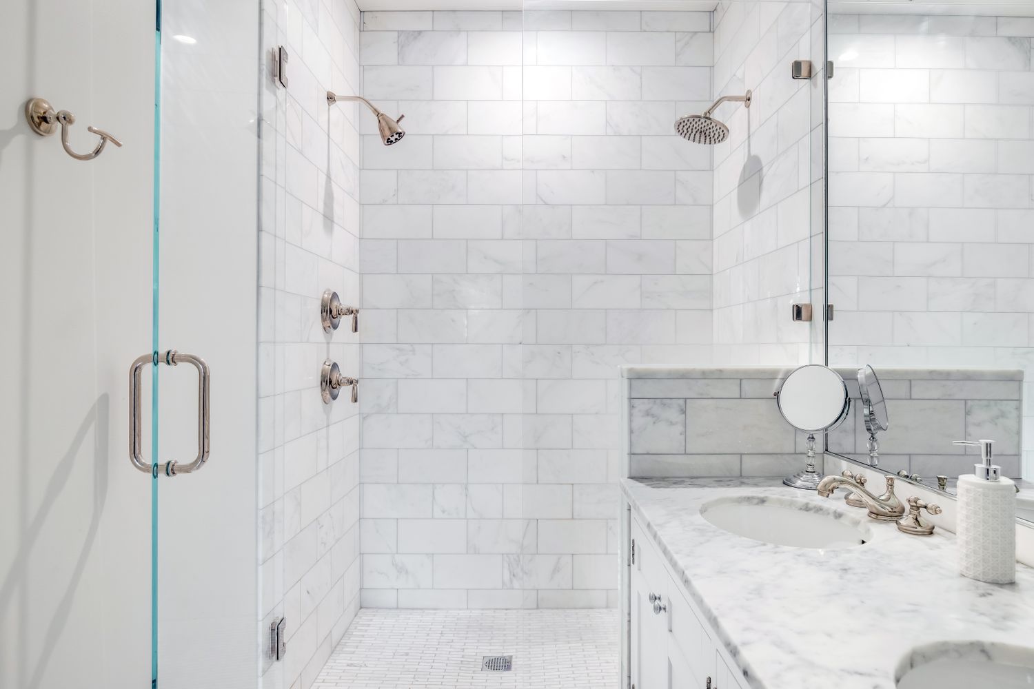 A modern bathroom with a marble countertop glass shower enclosures and tiled walls