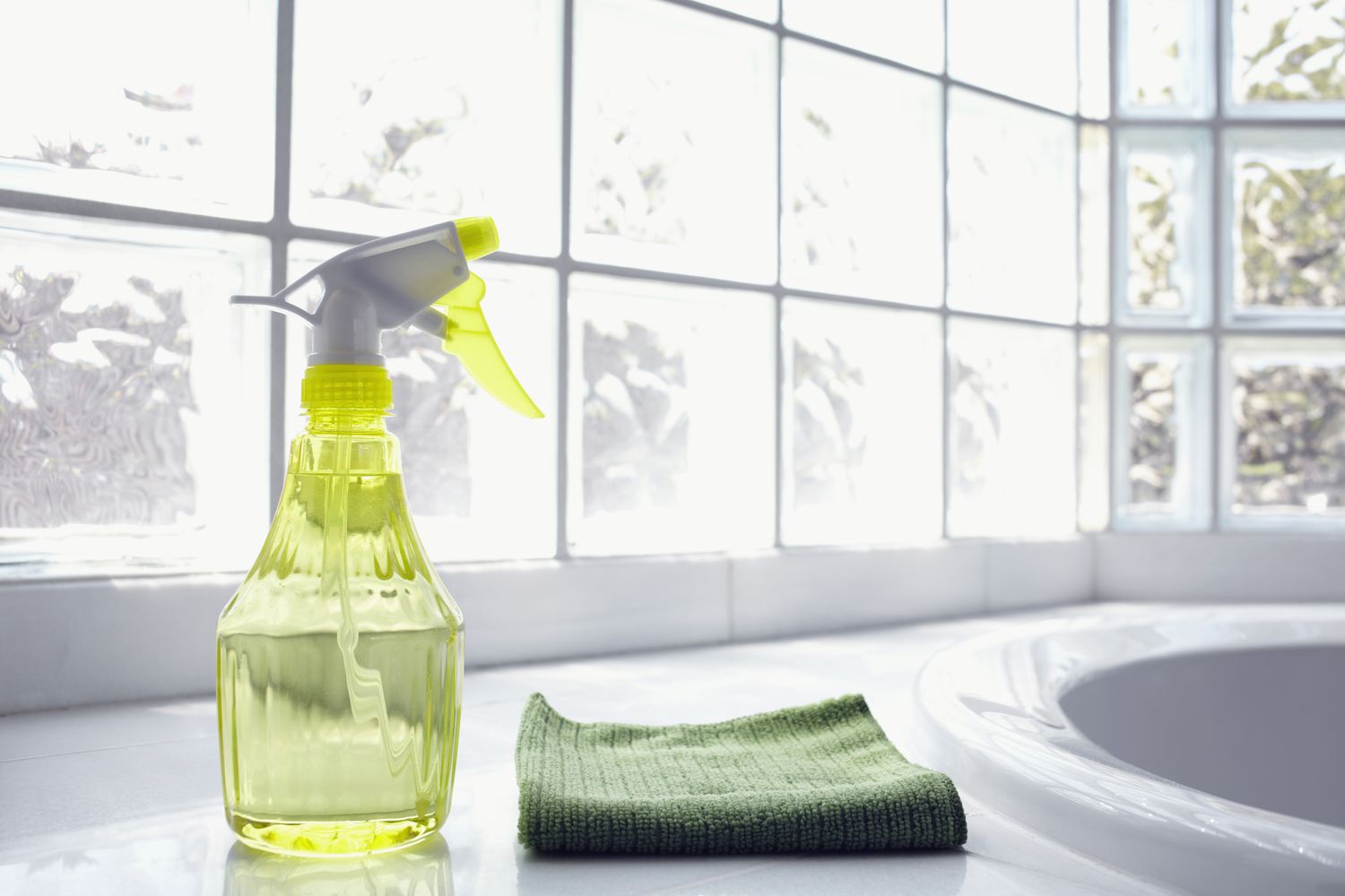 spray bottle and microfiber towel in front of windows