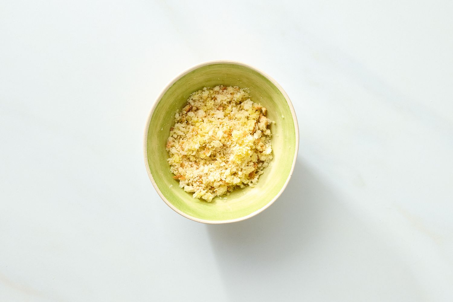 A bowl of rice topped with seasoning and ingredients positioned on a light background
