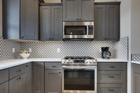 Modern kitchen with dark cabinets stainless steel appliances and patterned tile backsplash