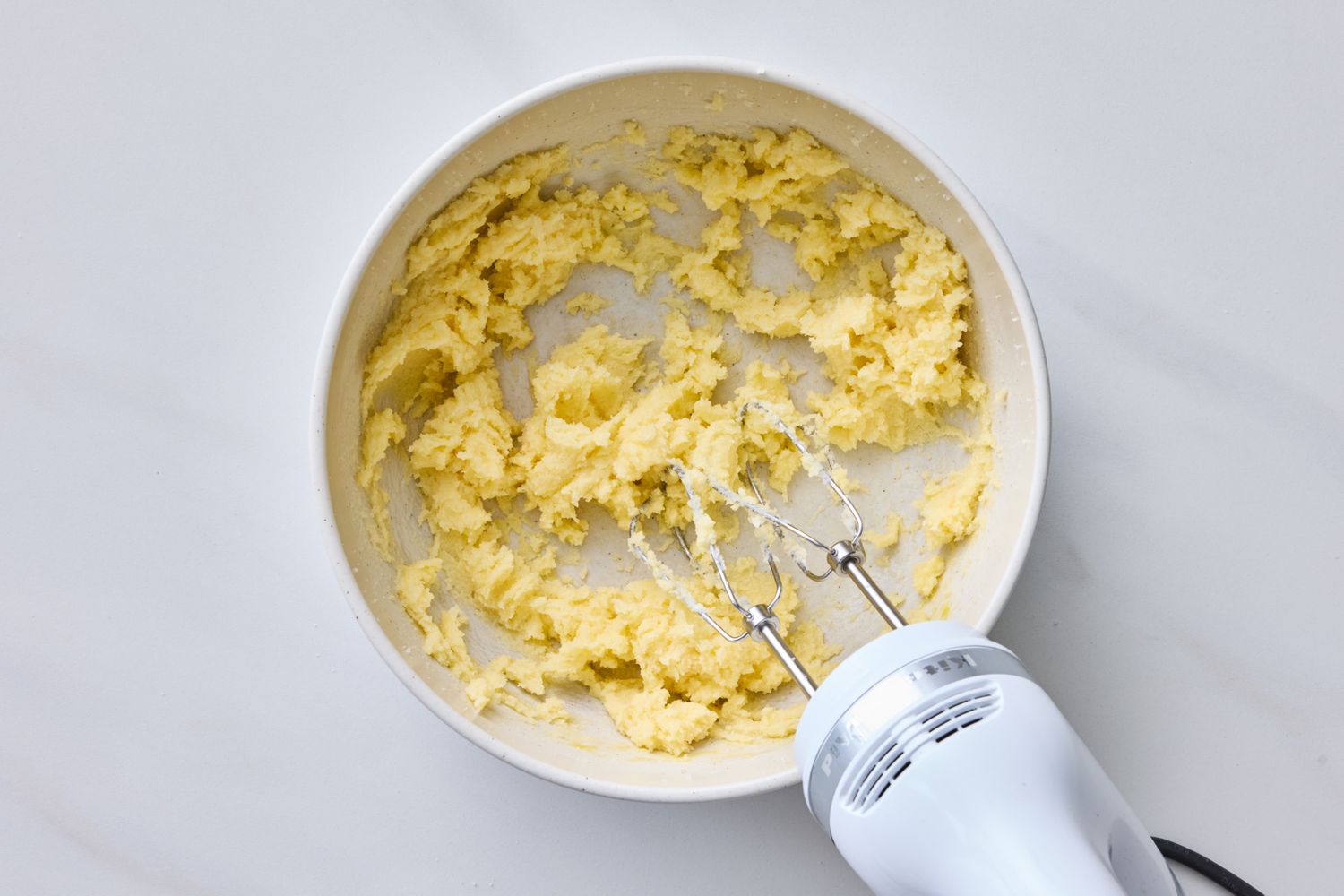 Batter in a mixing bowl with an electric hand mixer resting on the side