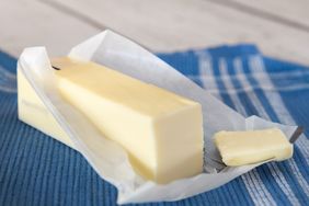stick of butter partially unwrapped on blue napkin