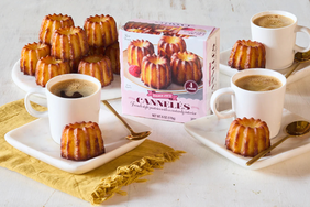 Plates with cannels and cups of coffee on a table alongside a box of cannels