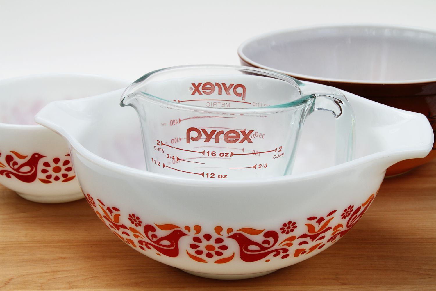  A PYREX clear glass measuring cup with several vintage Pyrex mixing bowls