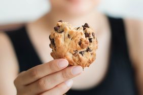 A person holding a partially eaten chocolate chip cookie