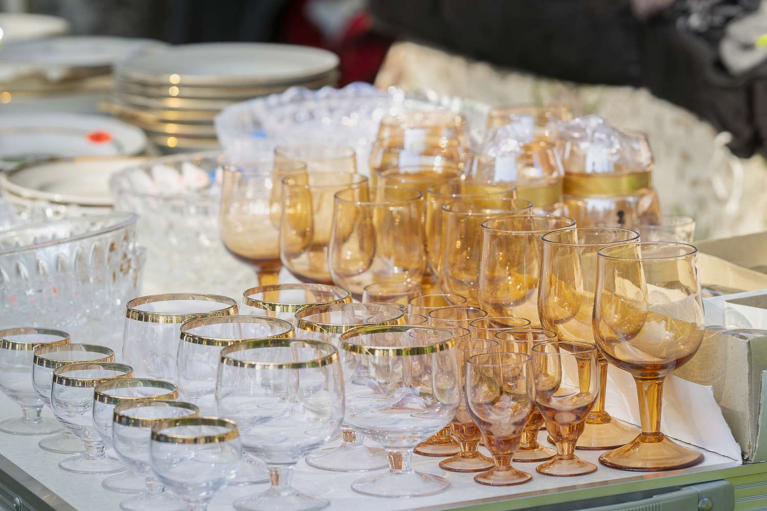 A display of assorted glassware including glasses and bowls arranged on a surface at a market setting