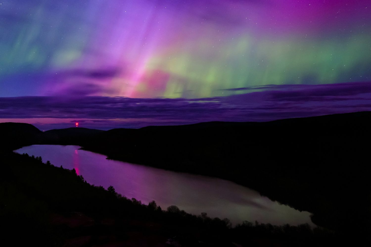 Northern Lights over a river and mountainous landscape at night
