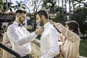 Family helping groom wearing a bowtie