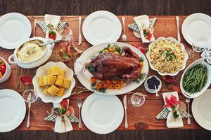 A festive dinner table set with various cooked dishes including a roasted poultry centerpiece corn cobs and green beans