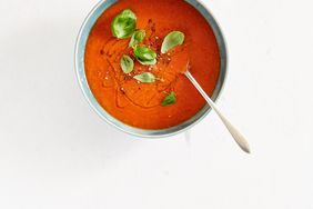 tomato soup in bowl with basil leaves garnish