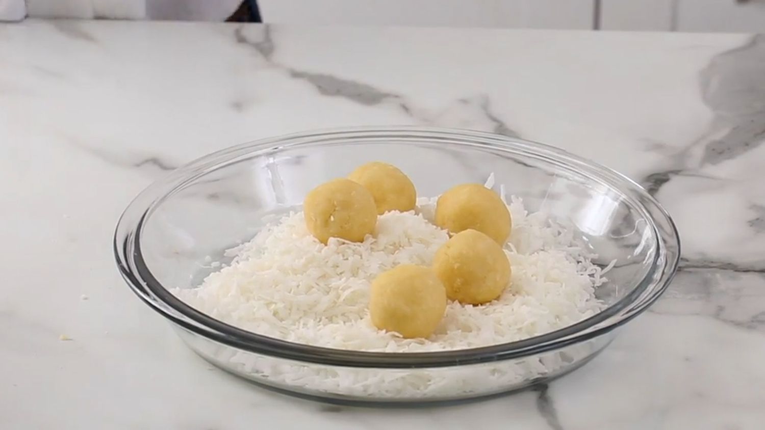 Rolling coconut cookies in coconut