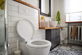 Toilet and sink in a tiled bathroom with a mirror and towel rack visible