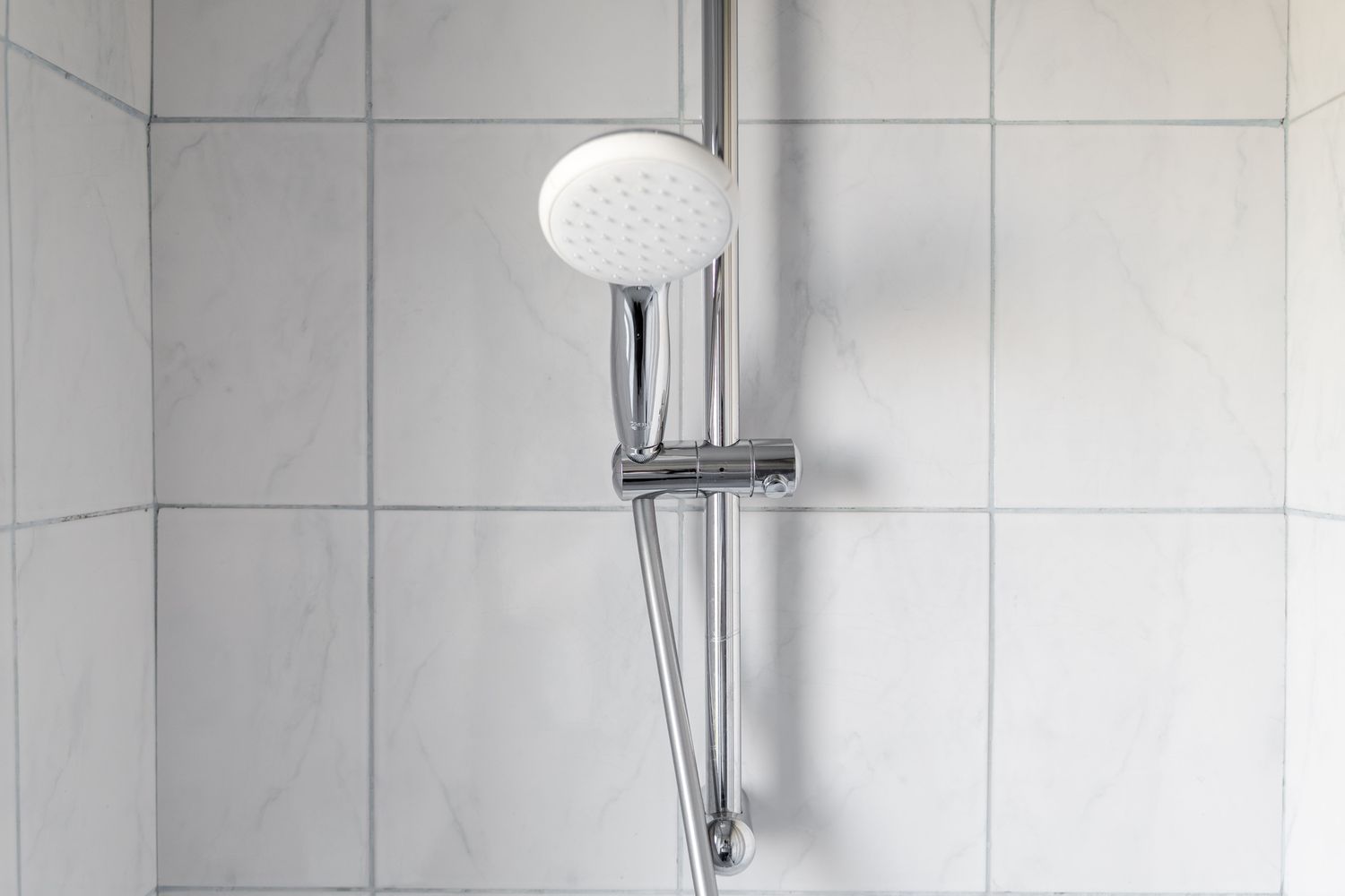 A modern shower head mounted on a tiled wall in a bathroom