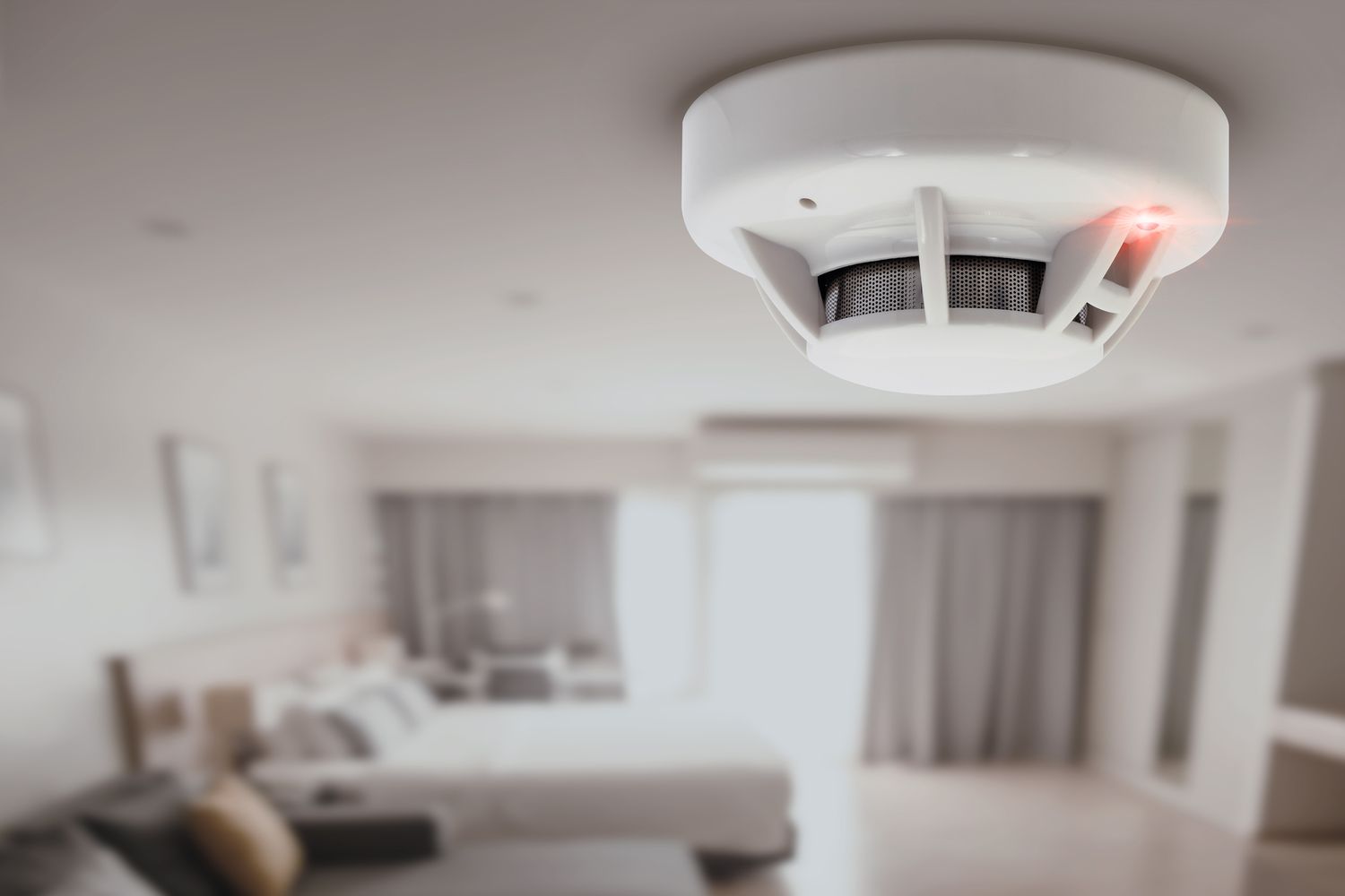 Ceilingmounted smoke detector in a room with blurred furniture in the background