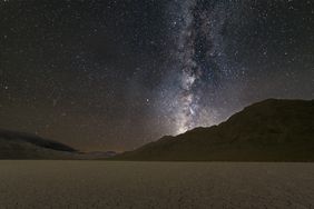 Night sky with the Milky Way visible over a mountainous desert landscape