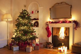 Decorated Christmas tree with presents by a fireplace mantel adorned with stockings and garlands cozy holiday setting