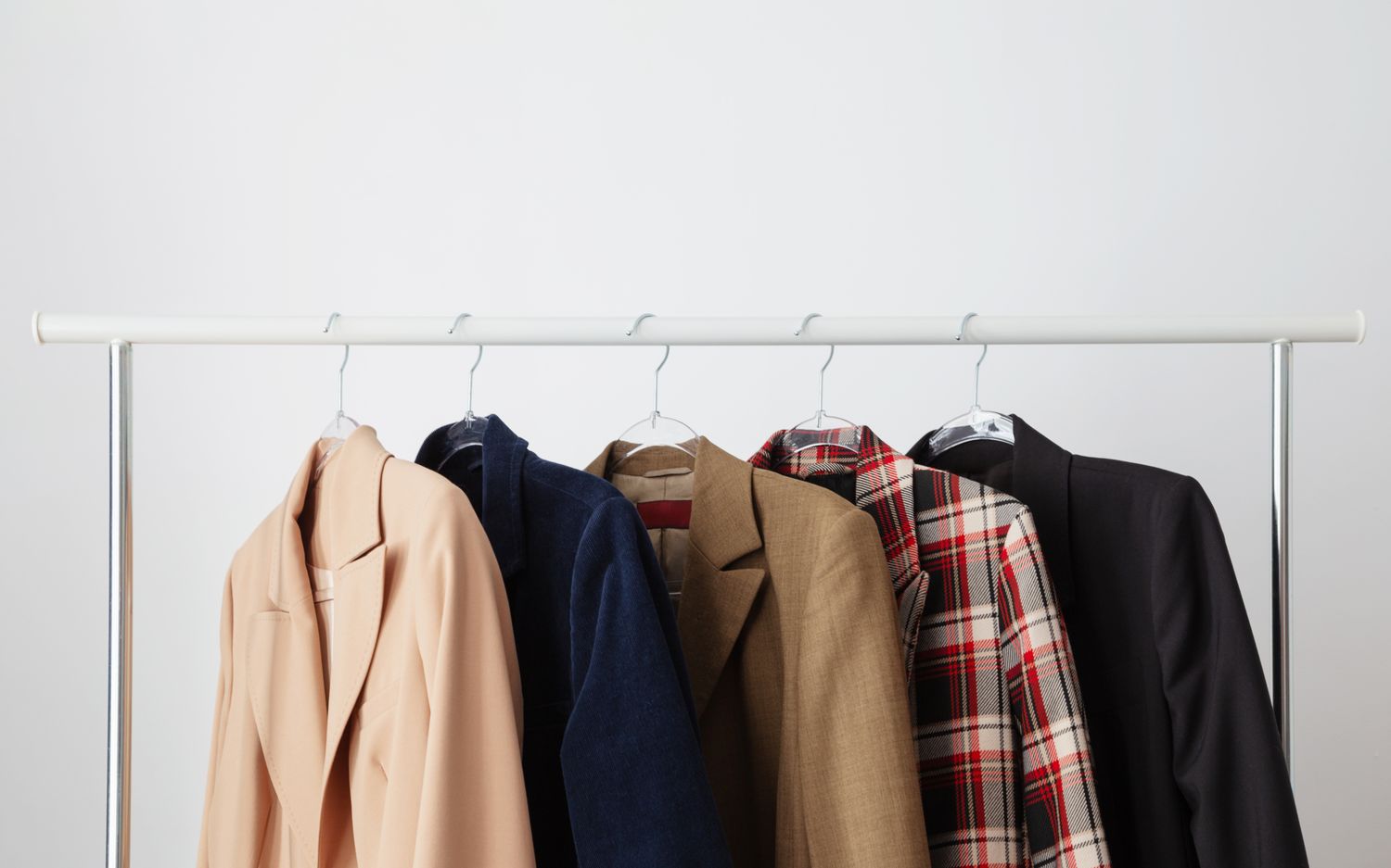 A row of coats hanging on garment hangers on a rack various styles and designs visible