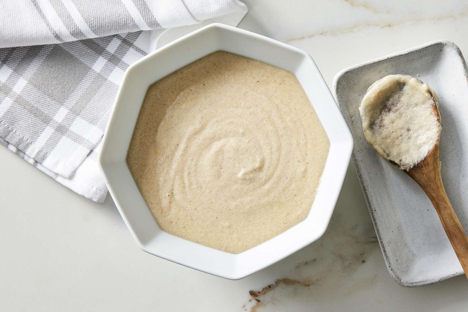 croque monsieur sauce in white bowl with wooden spoon