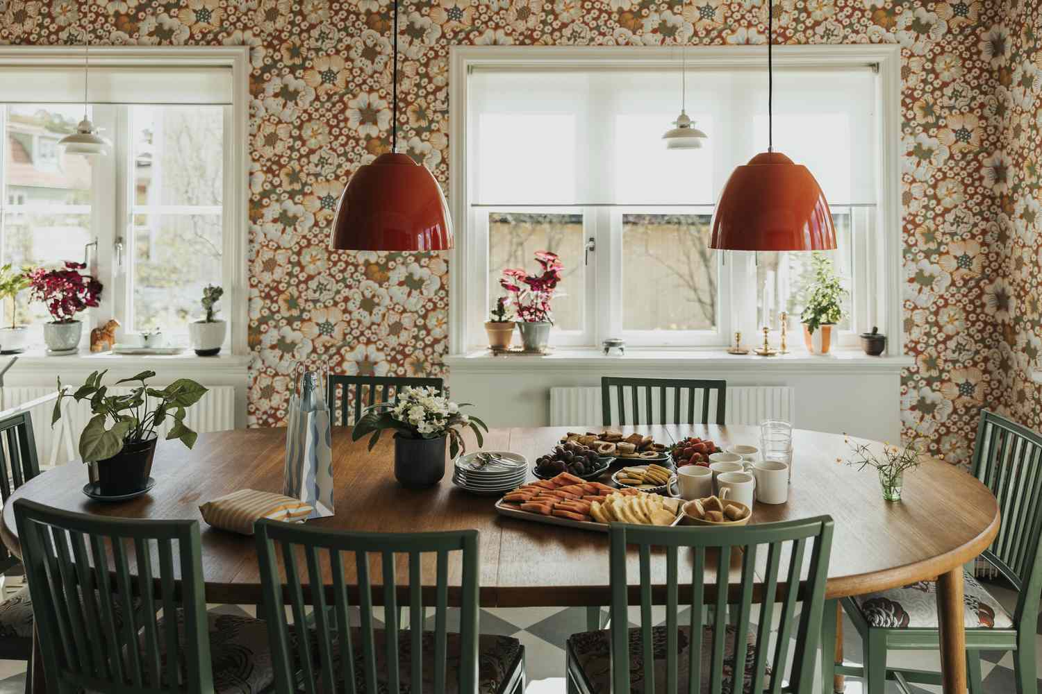 A dining table set with food and drinks surrounded by green chairs in a welllit room