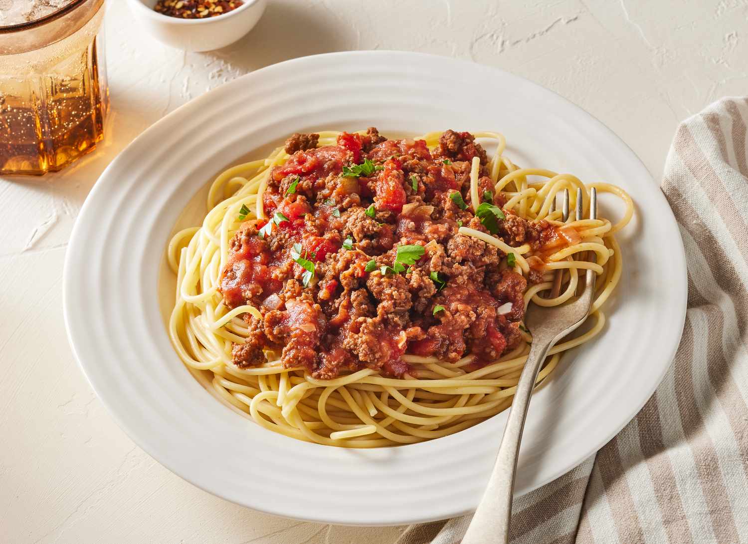 white plate of meat spaghetti sauce and pasta with fork