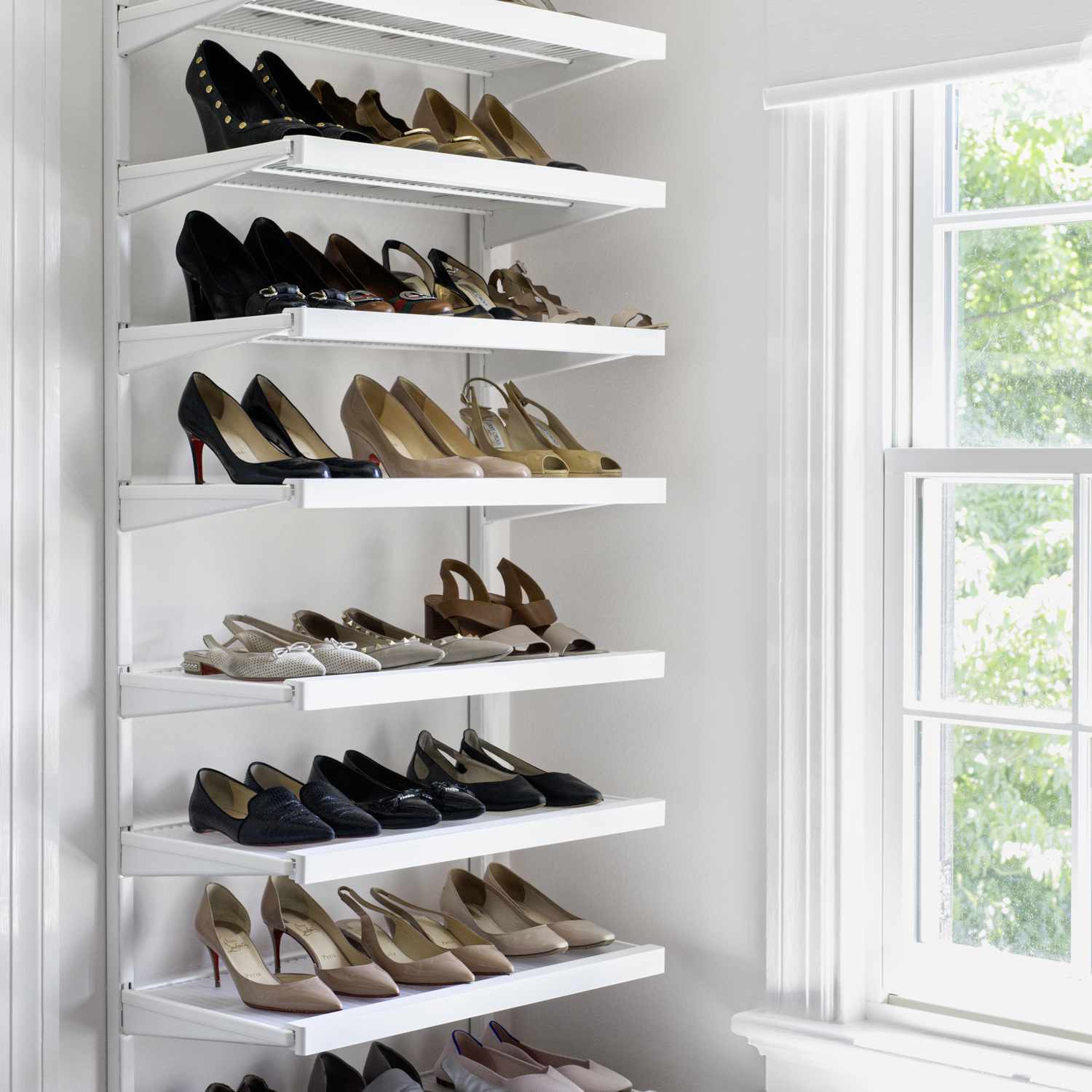 white shoe rack filled with multiple pairs of high heels 