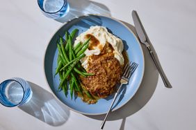 Salisbury steak with onion gravy mashed potatoes and green beans on a plate