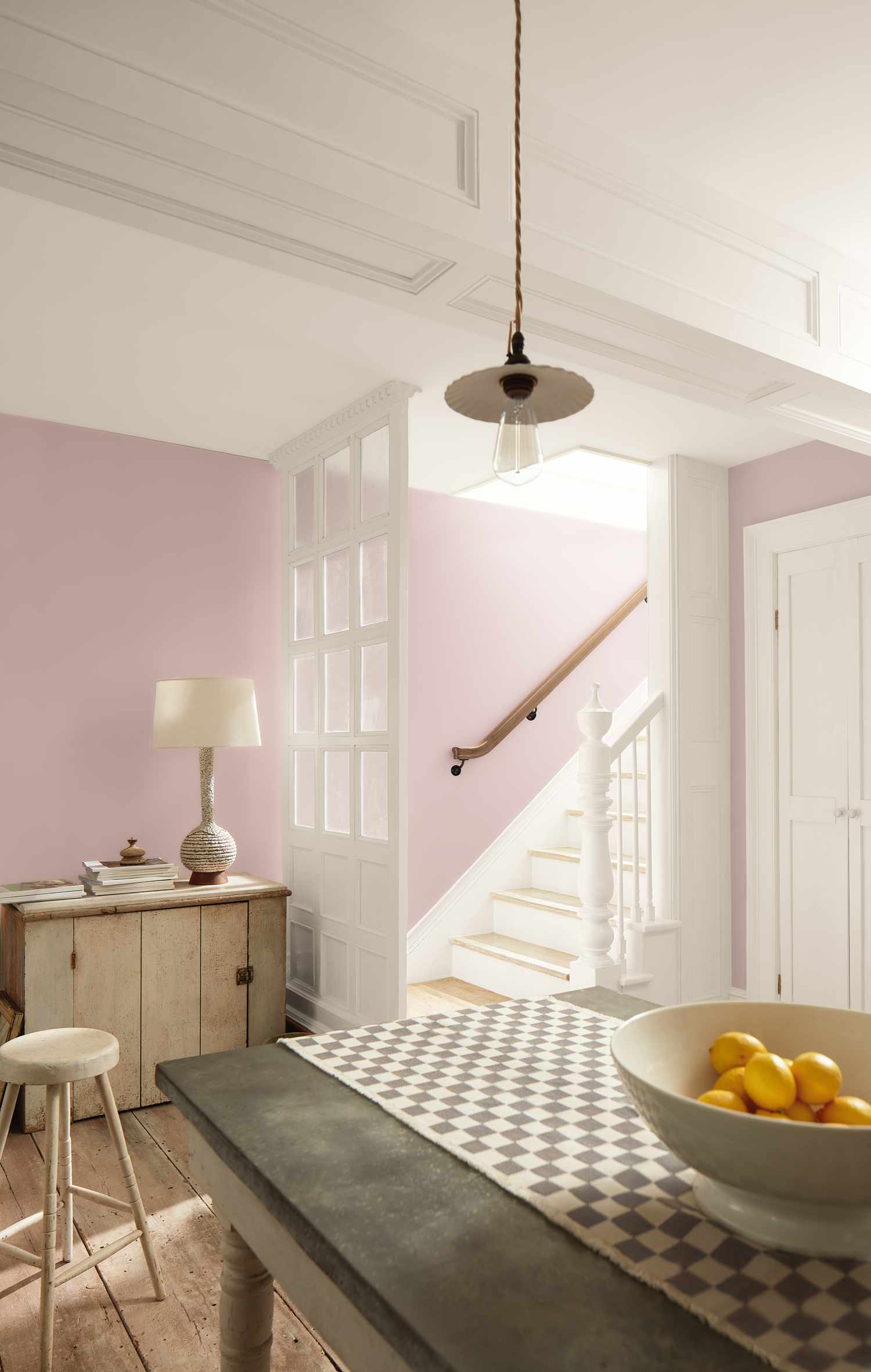 A cozy room with a table lamp sideboard and staircase in the background