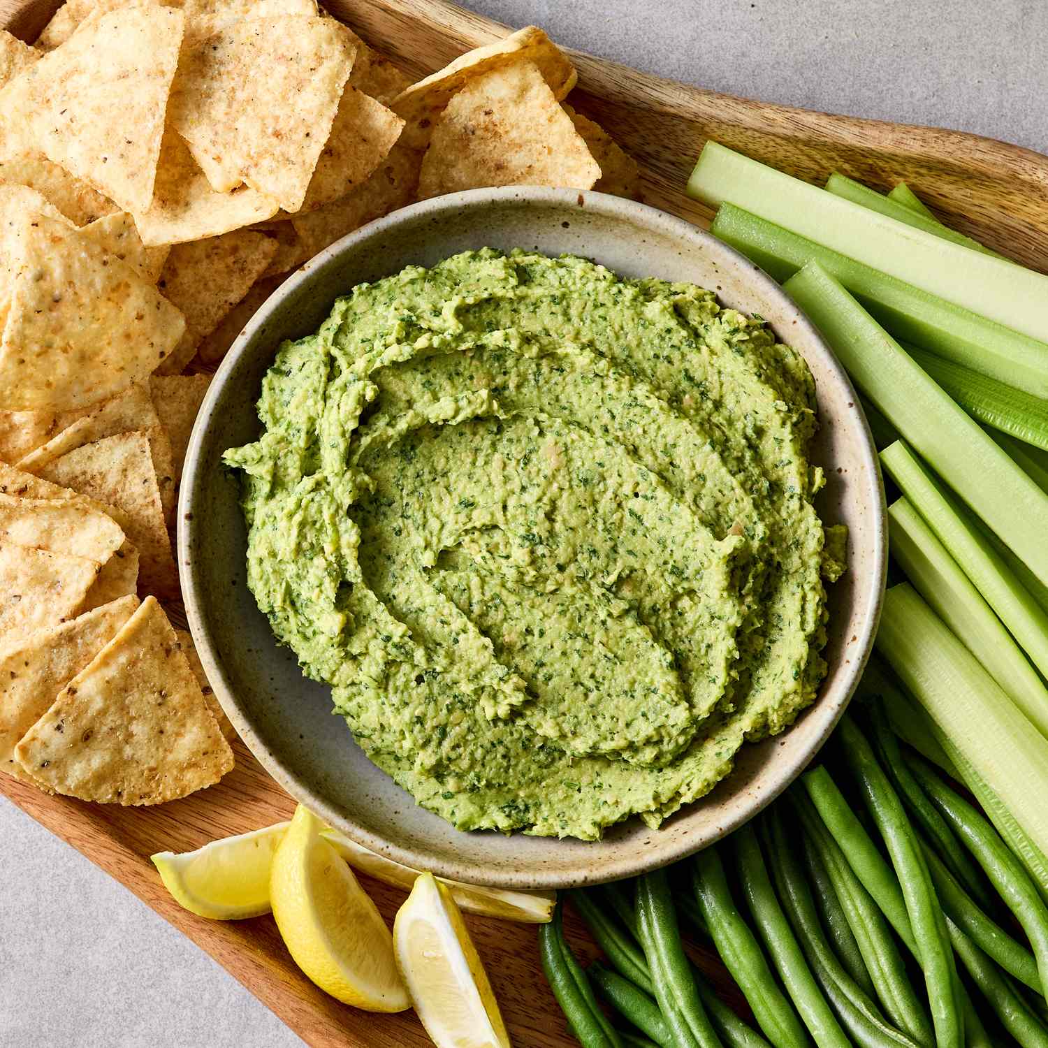 Guacamole hummus with tortilla chips and vegetables for dipping on a platter