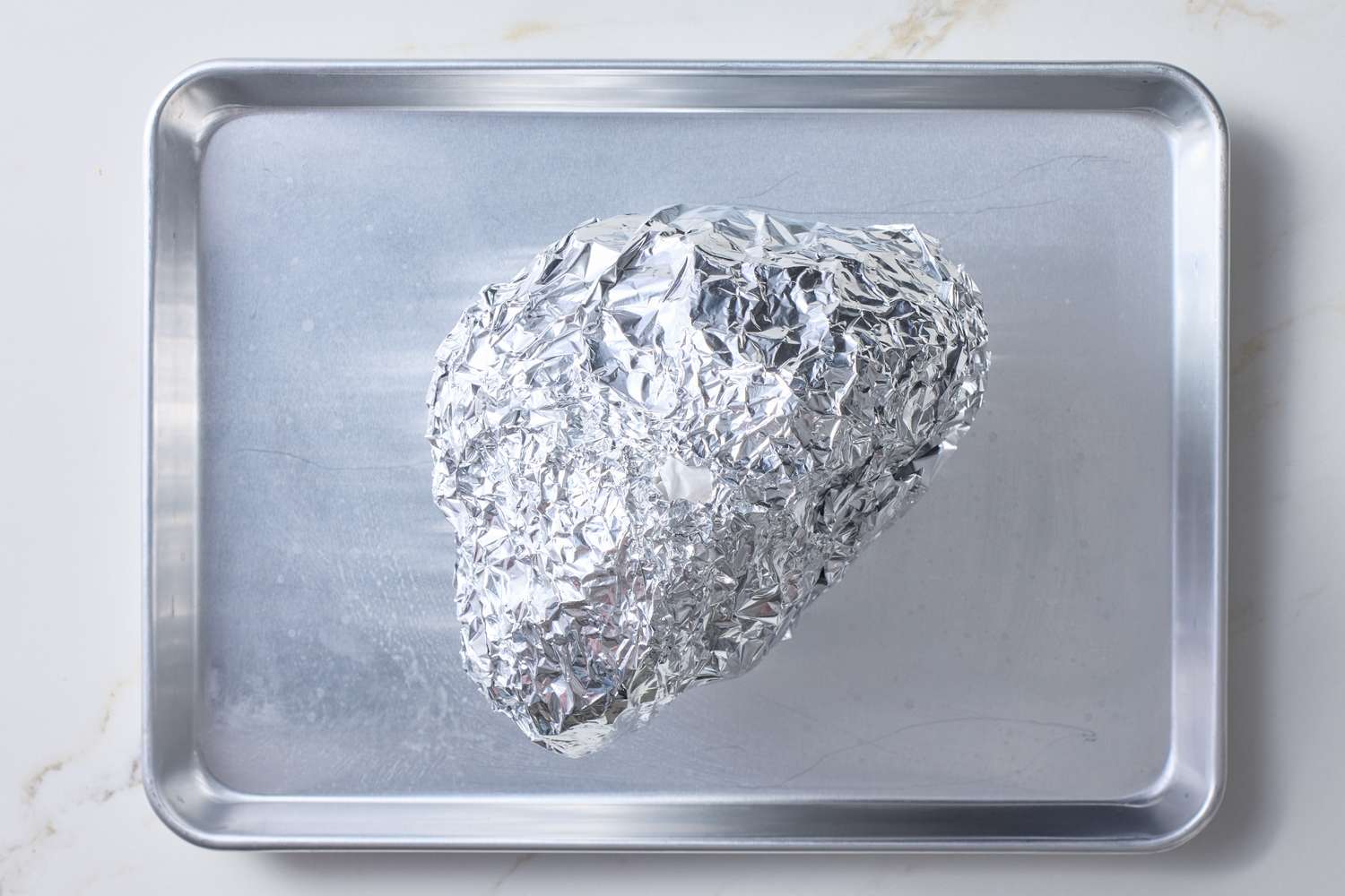 A foilwrapped item placed on a metal baking sheet