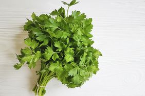 bunch of fresh parsley on white wooden surface