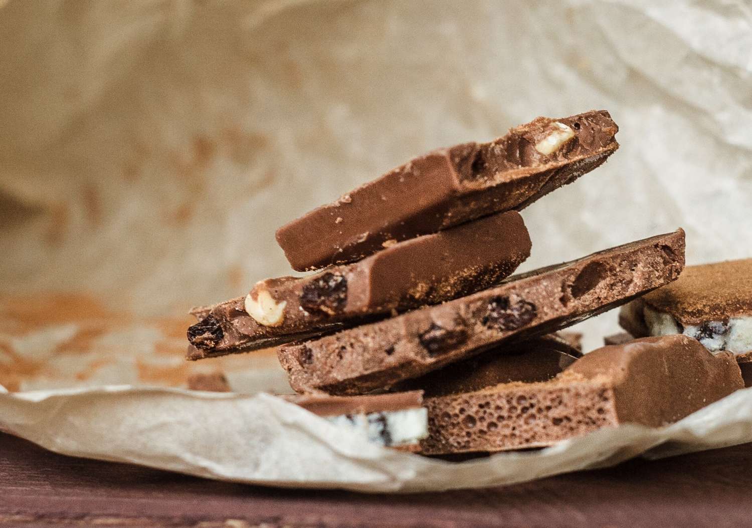 Stack of chocolate bark with nuts and raisins on parchment paper