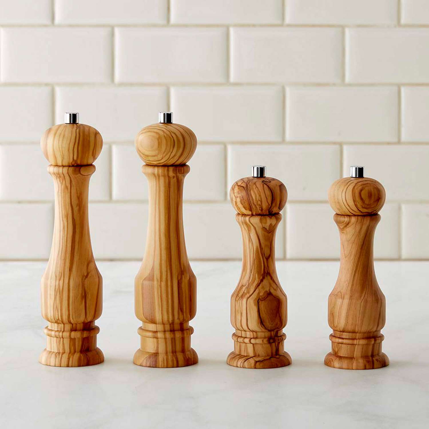 Set of four olivewood salt and pepper mills in varying sizes on a countertop