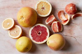 Whole and sliced grapefruits on a marble surface