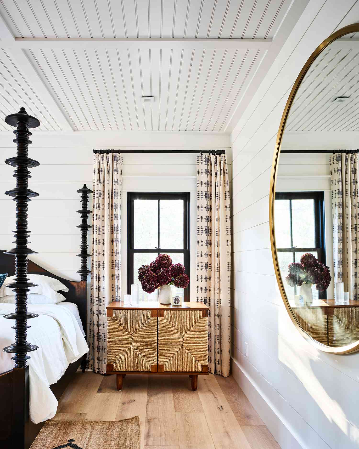 bedroom with a large round mirror and wicker nightstand
